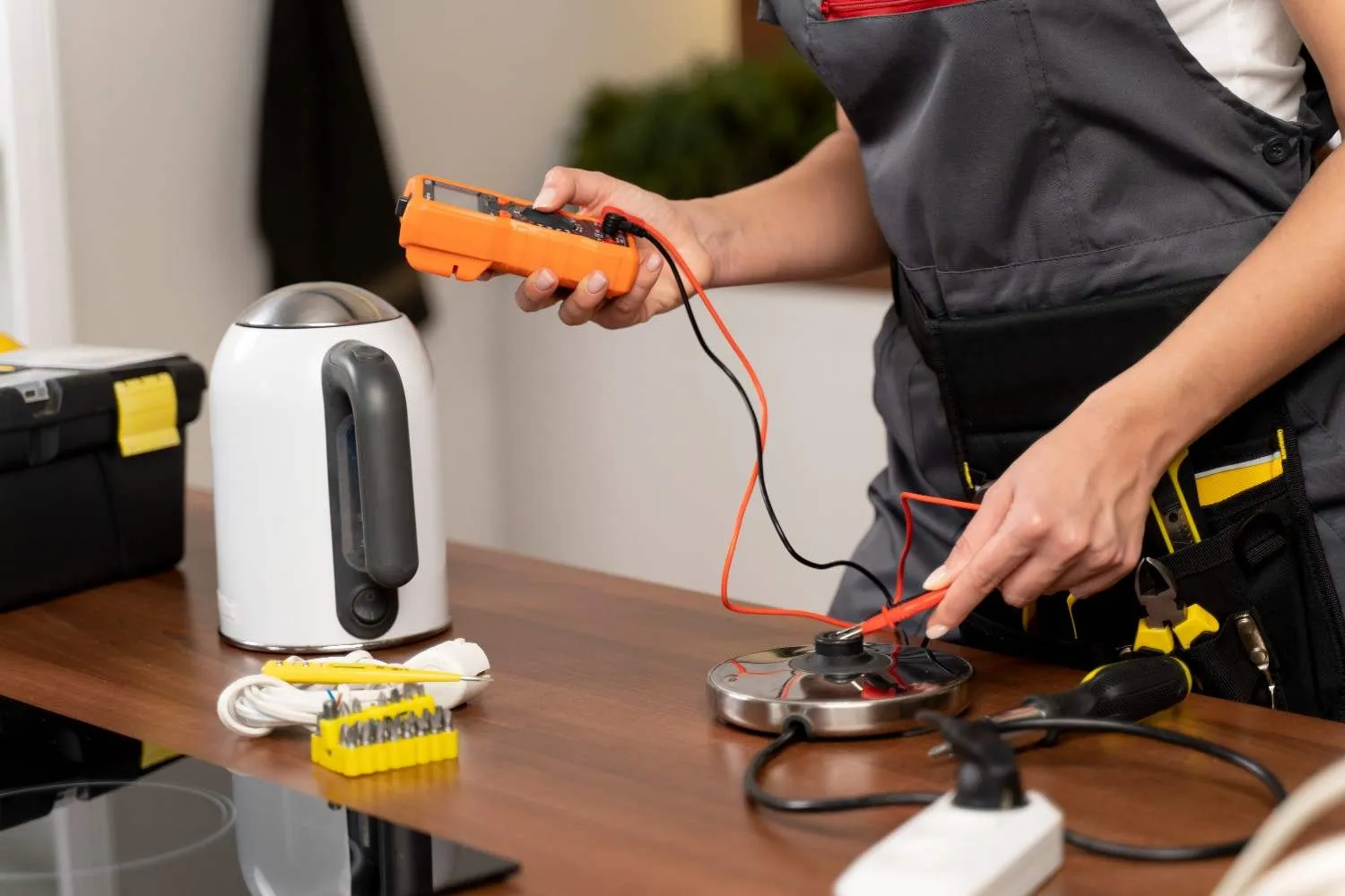 Technician testing a kitchen appliance part with a multimeter